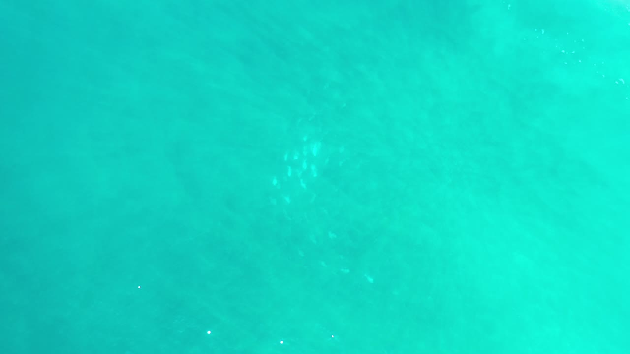 Turquoise ocean water with faint ripples and darker patches below the surface.