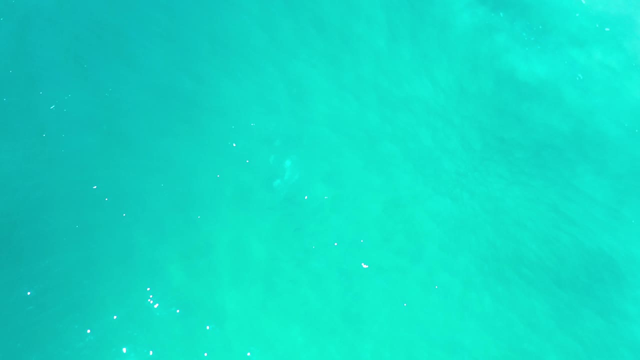 Blue-green sea surface in Los Cabos, Mexico, with subtle wind ripples and scattered white highlights, no visible people.