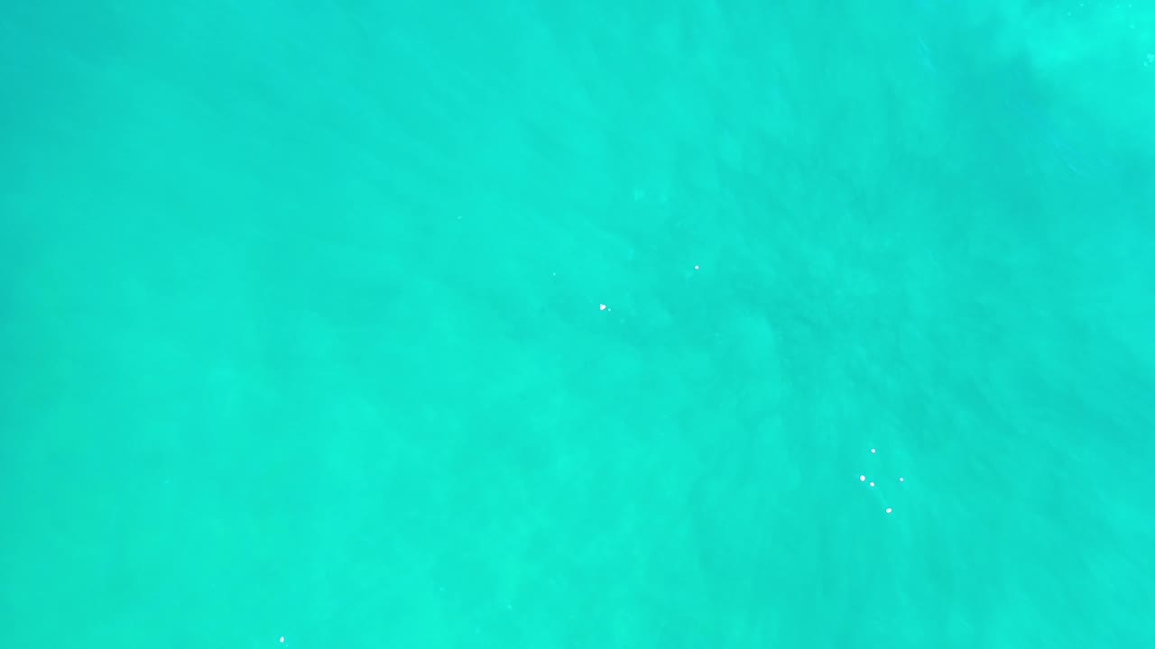 Light blue Los Cabos water fills the frame with shallow-looking ripple patterns and a few tiny surface highlights, no visible people.