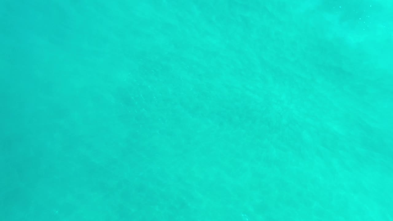 Clear blue-green water in Los Cabos, Mexico shows small surface highlights near the lower portion of the frame, with no visible people or shoreline.