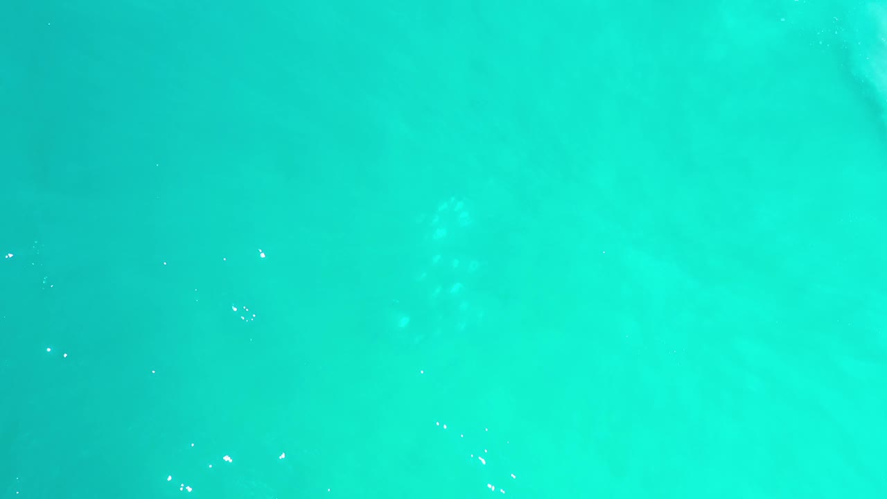Green blue ocean water in Los Cabos, Mexico, seen from above with scattered bright reflections and no visible people.