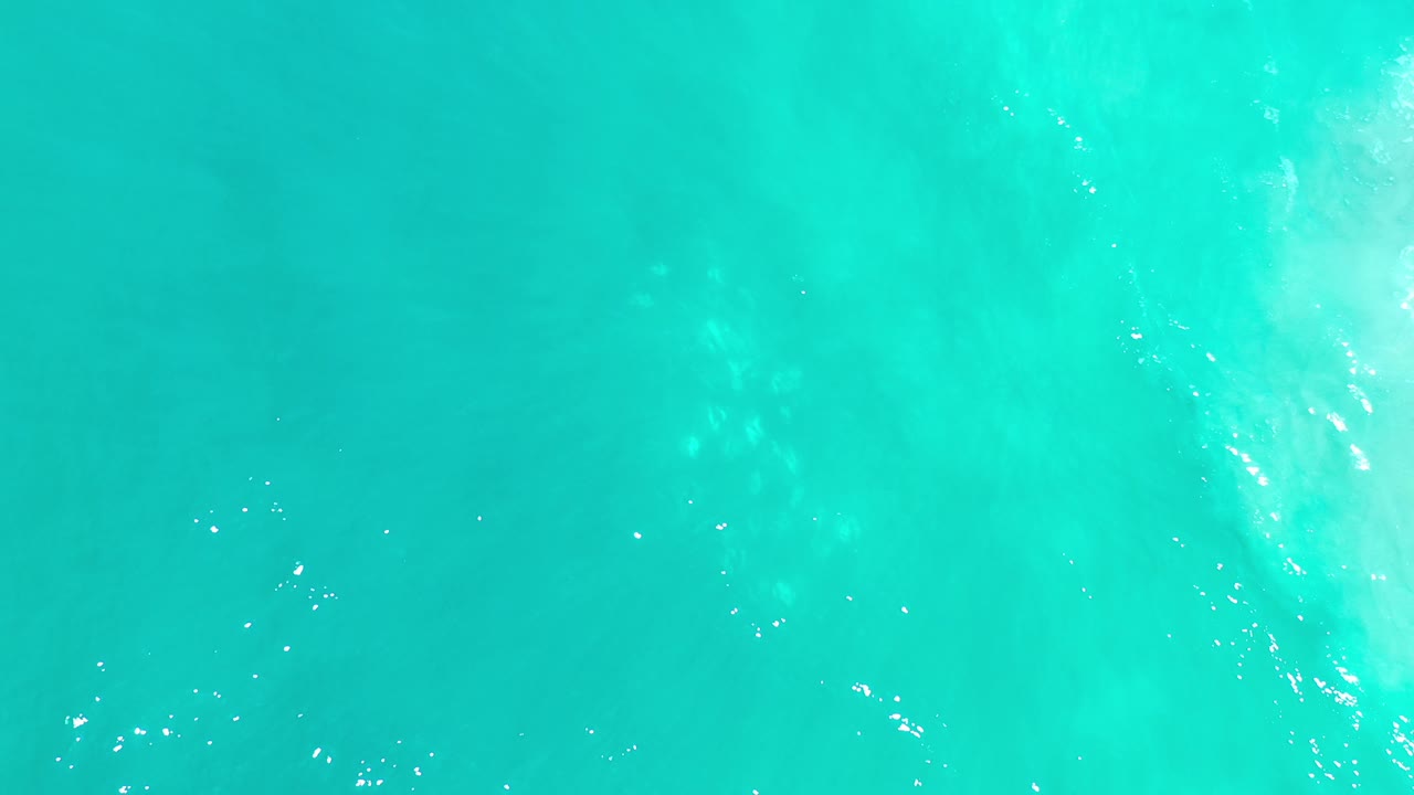 Bright turquoise water with sandy shapes below.