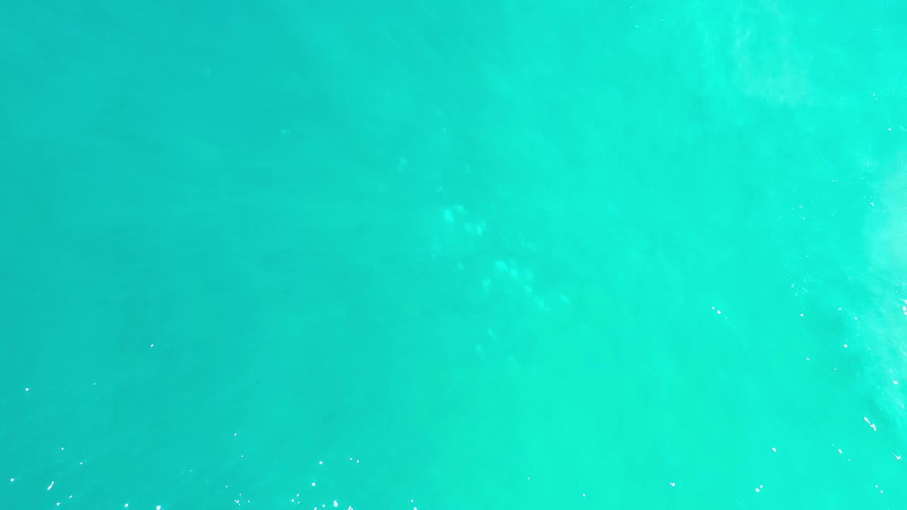 Green-blue sea surface in Los Cabos, Mexico, with soft tonal shifts and scattered tiny white glints, no visible people.