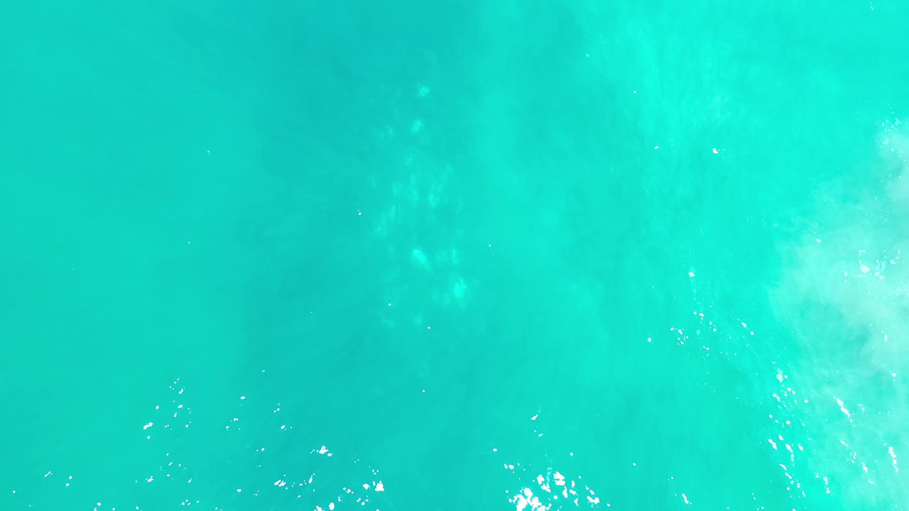 Bright teal ocean with a small white wave area in the middle.
