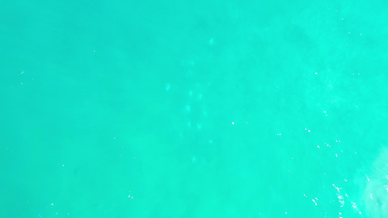 Overhead view of bright turquoise water in Los Cabos, Mexico, with soft submerged texture and no visible people.