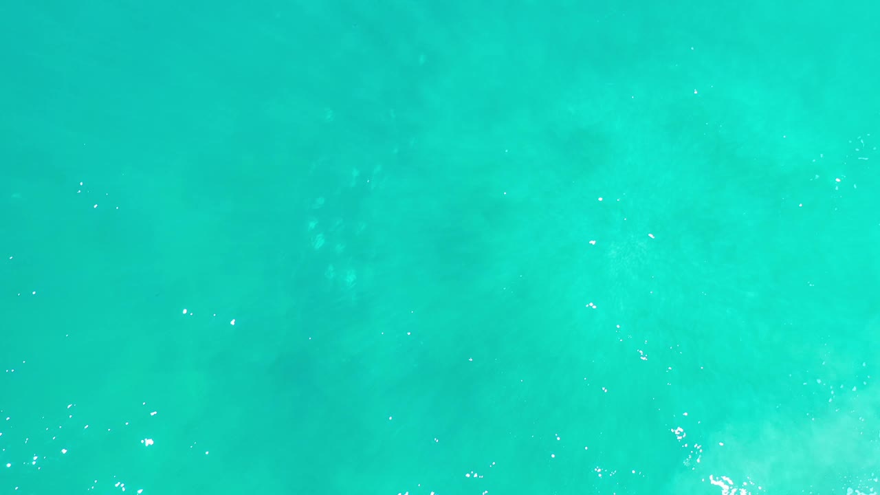 Aqua water fills the frame in Los Cabos, Mexico, with soft cloudy color shifts below the surface and no visible people.
