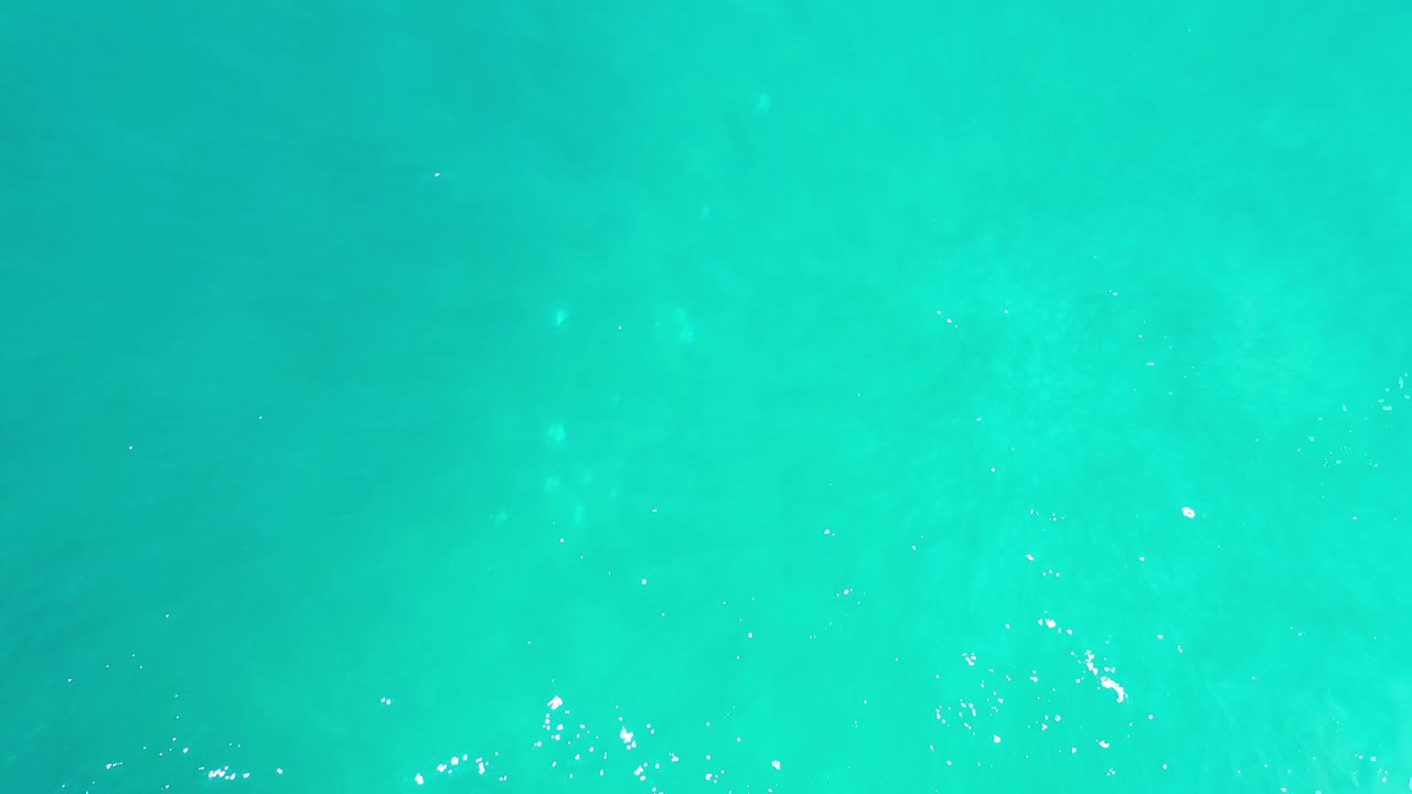 Green blue ocean water in Los Cabos fills the frame, with scattered white highlights on the surface and no visible people.