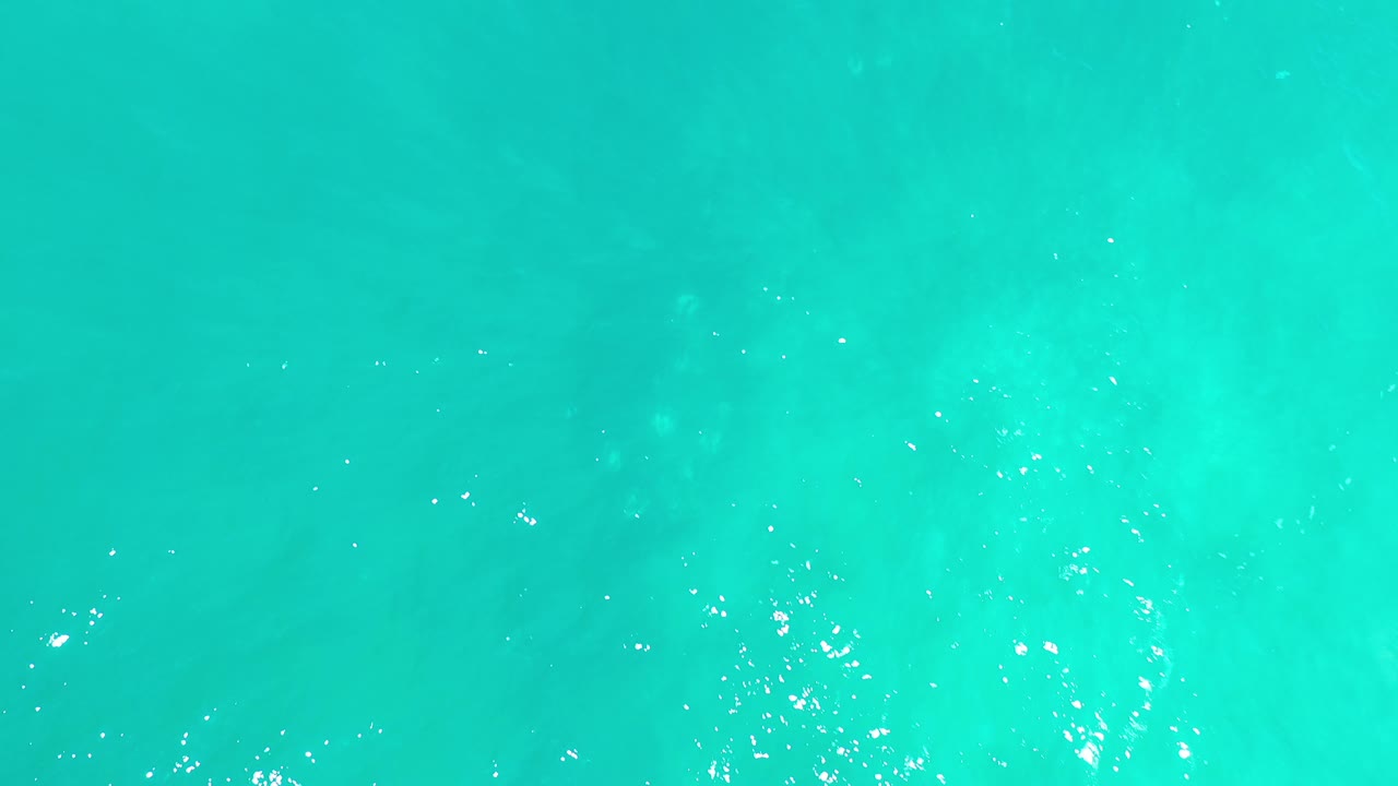 Bright aqua water with small white reflection clusters.