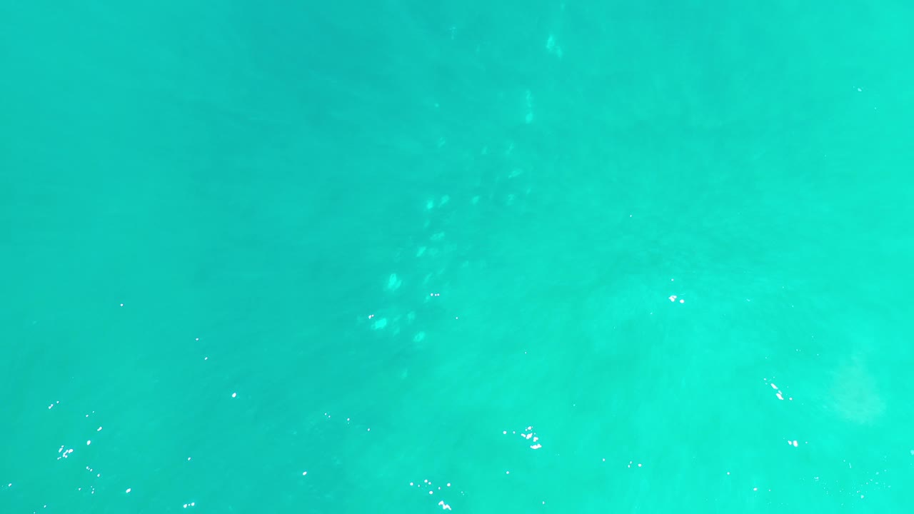 Open turquoise sea with soft cloudy patterns below the surface.