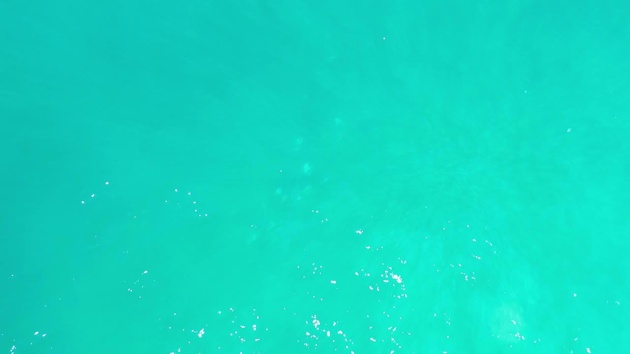 Calm turquoise sea surface with faint lighter streaks.