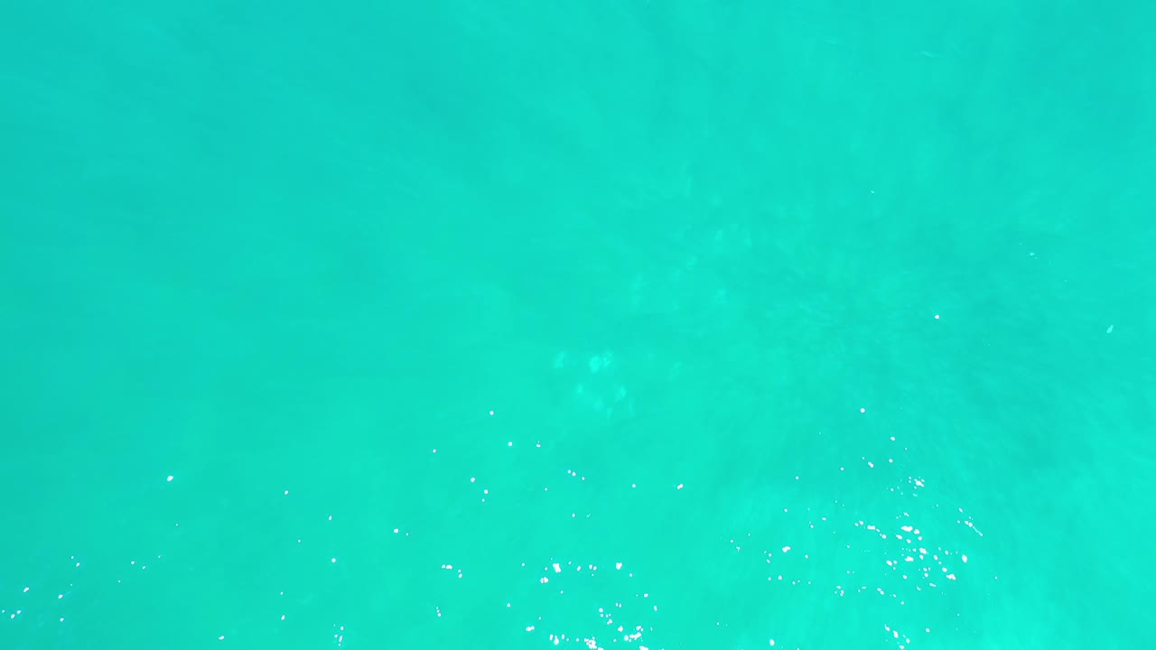 Overhead Los Cabos ocean water fills the frame, with pale green tonal shifts, fine ripple marks, and no visible people.