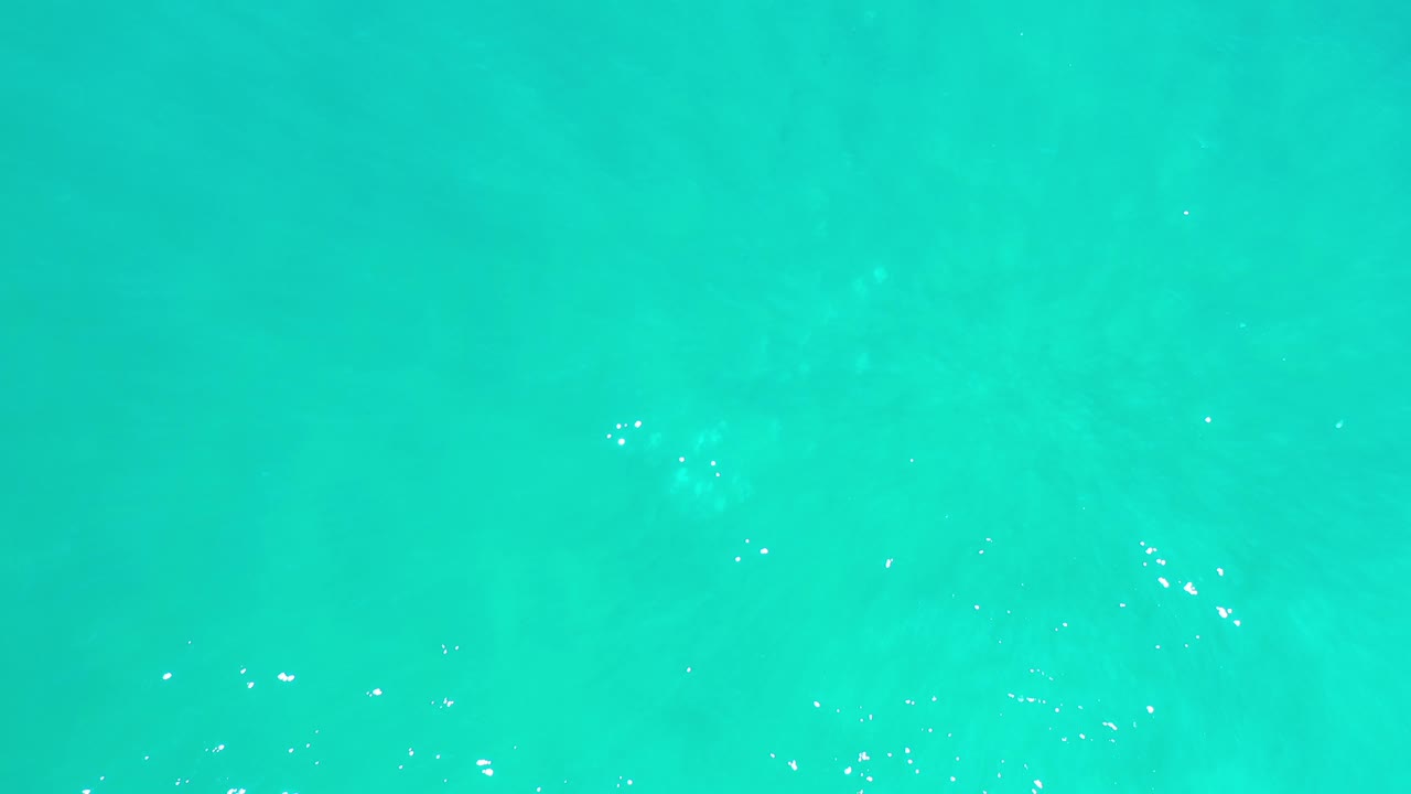 Turquoise water with scattered white reflections.