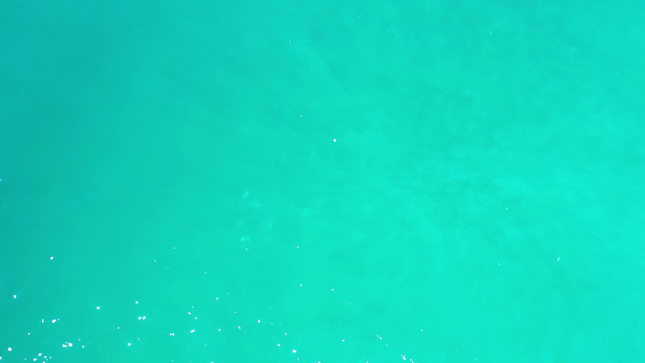 Clear turquoise water with faint mottled areas beneath the surface.