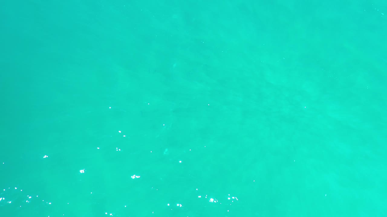 Bright aquamarine water with scattered white sparkles.