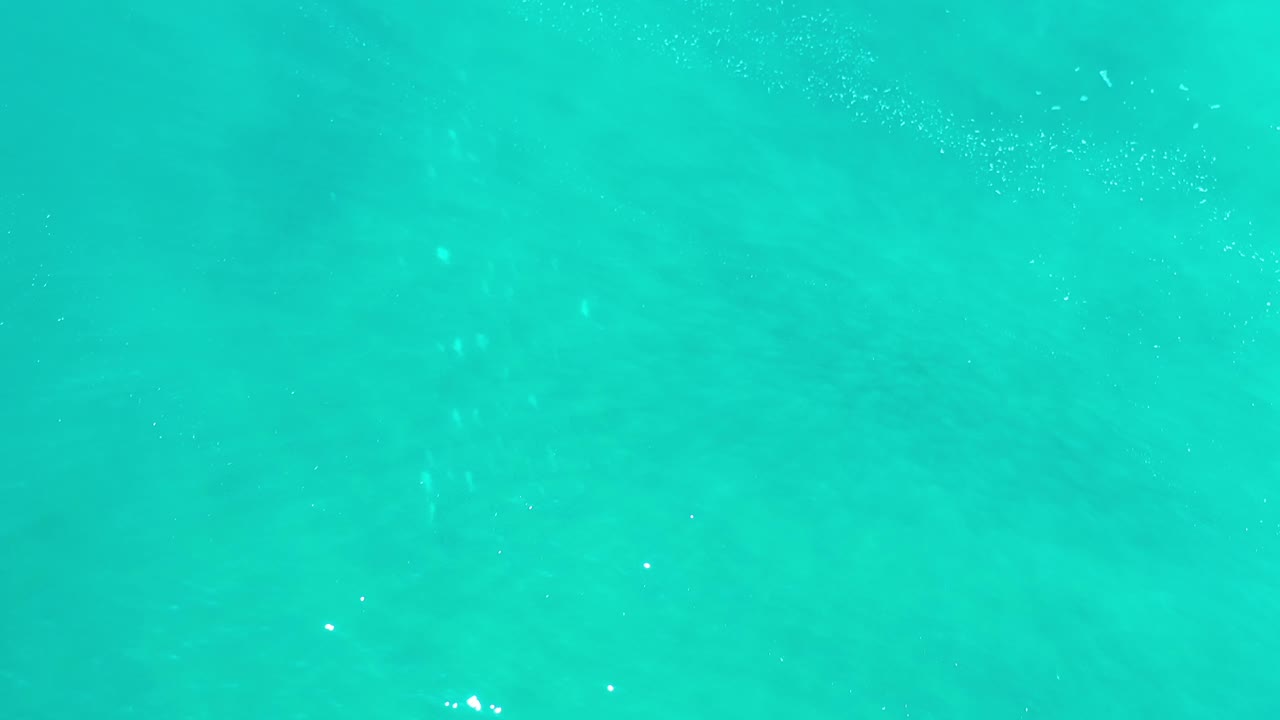 Green-blue ocean surface in Los Cabos, Mexico, with soft diagonal wave bands, light shimmer, and no visible people.