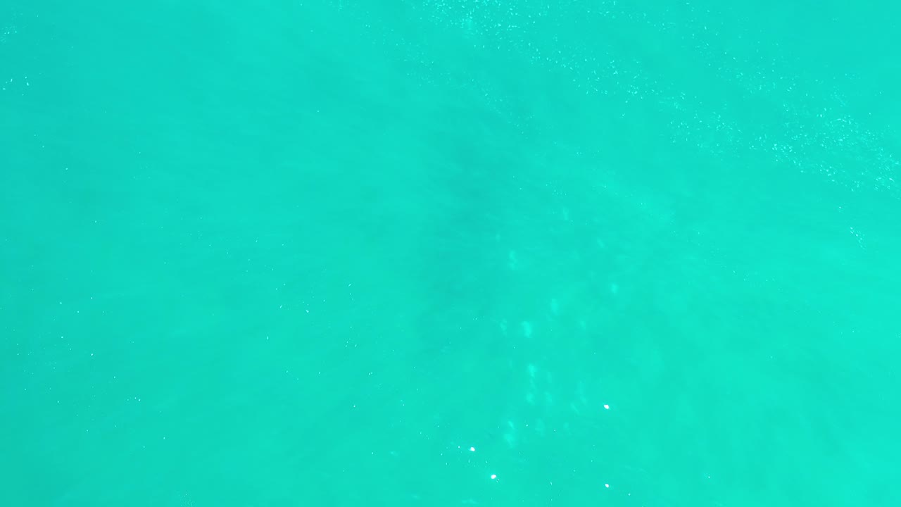 Turquoise ocean water with faint ripples and foam specks.