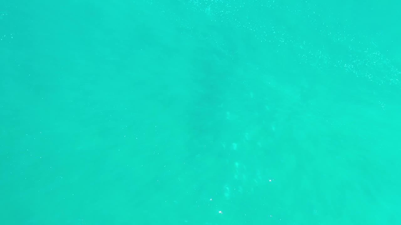 Blue-green water in Los Cabos fills the frame with small bright flecks on the surface and no land, boats, or visible people.