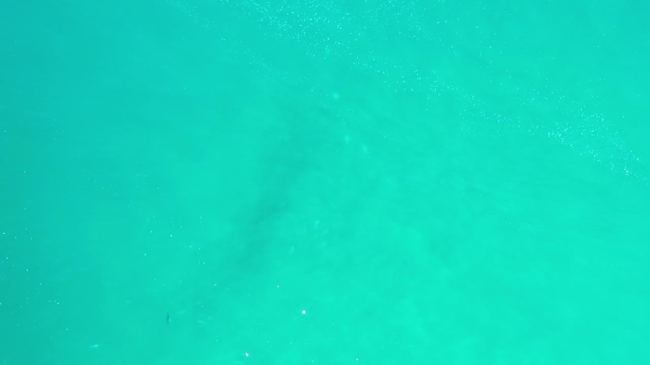 Clear aqua water with darker underwater patches.