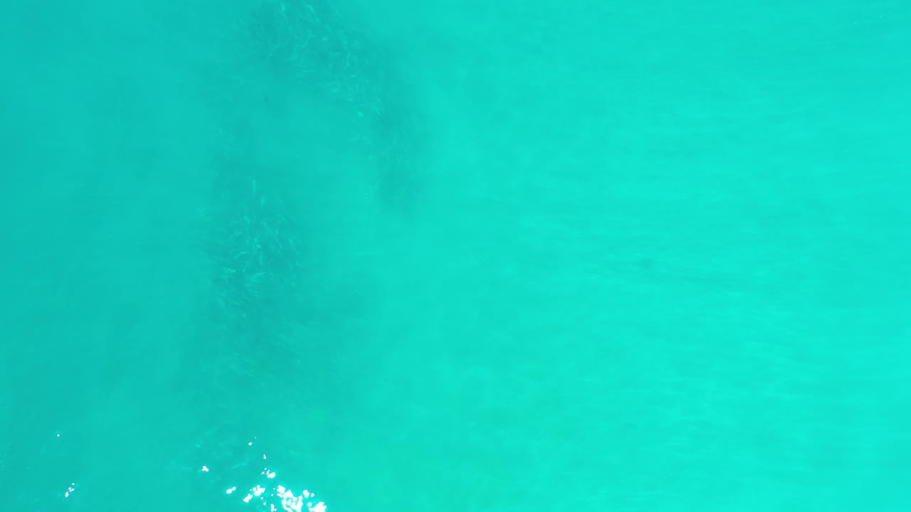 Clear aqua water with a bright cluster of reflections.