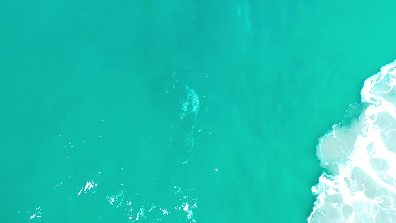 Bright aqua water with a white foam break along the right side.