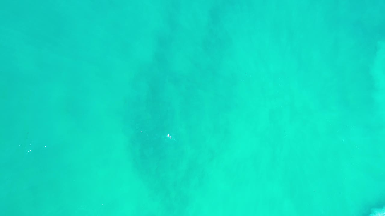 Overhead turquoise water in Los Cabos, Mexico, with faint darker patches beneath the surface and no visible people.