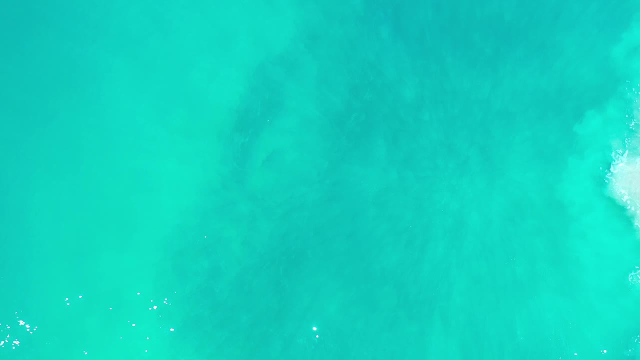 Turquoise sea surface with scattered tiny white ripples.
