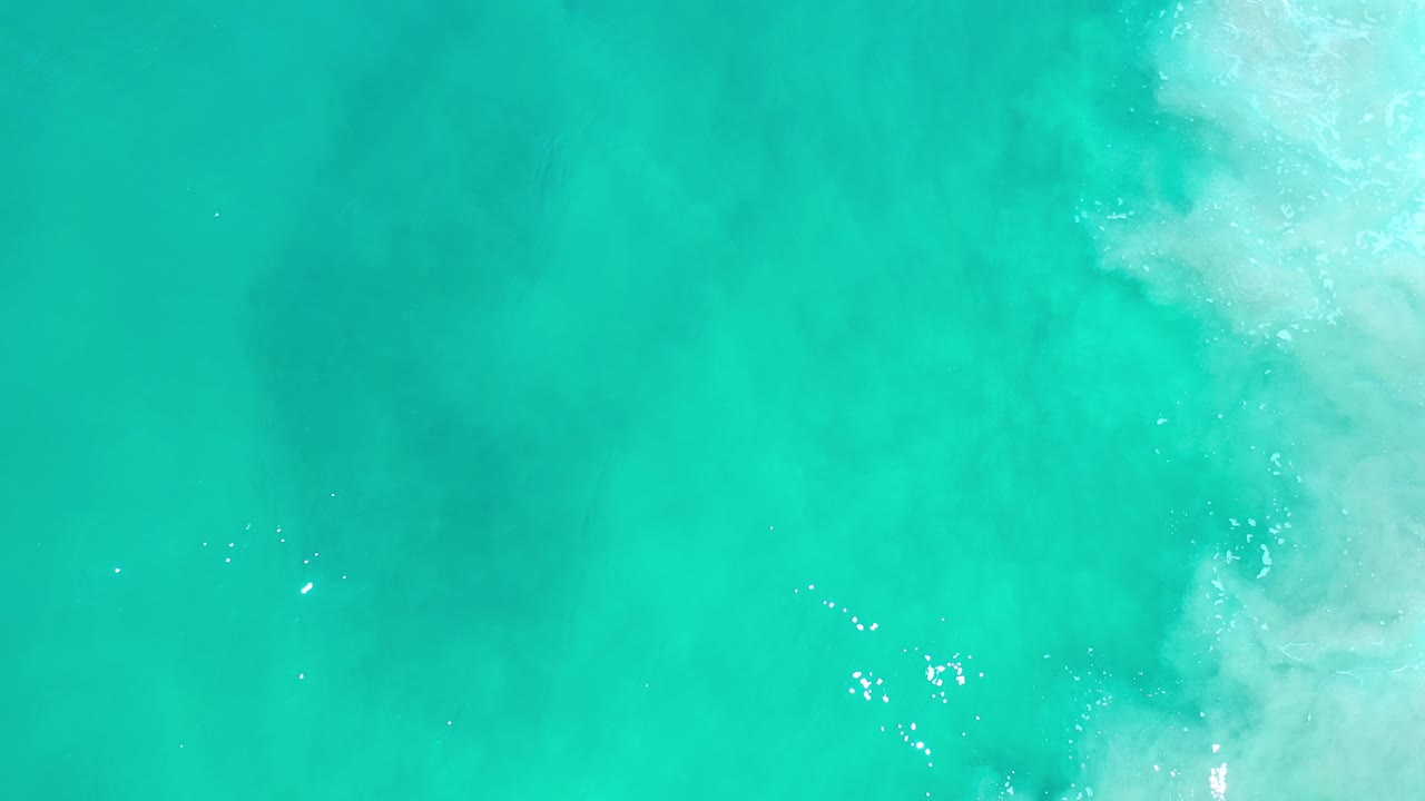 Teal seawater with soft foam at the upper right.