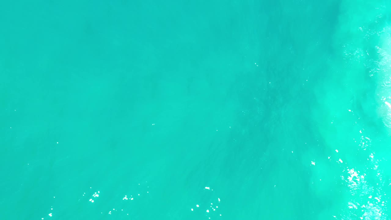 Blue-green Los Cabos water fills the frame from above, with a broad soft pale area under the surface and no visible people.