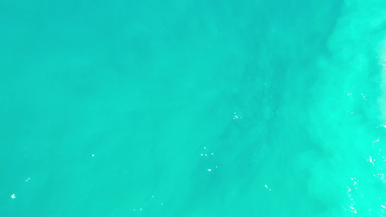 Turquoise ocean surface with small bright reflections near the lower area.