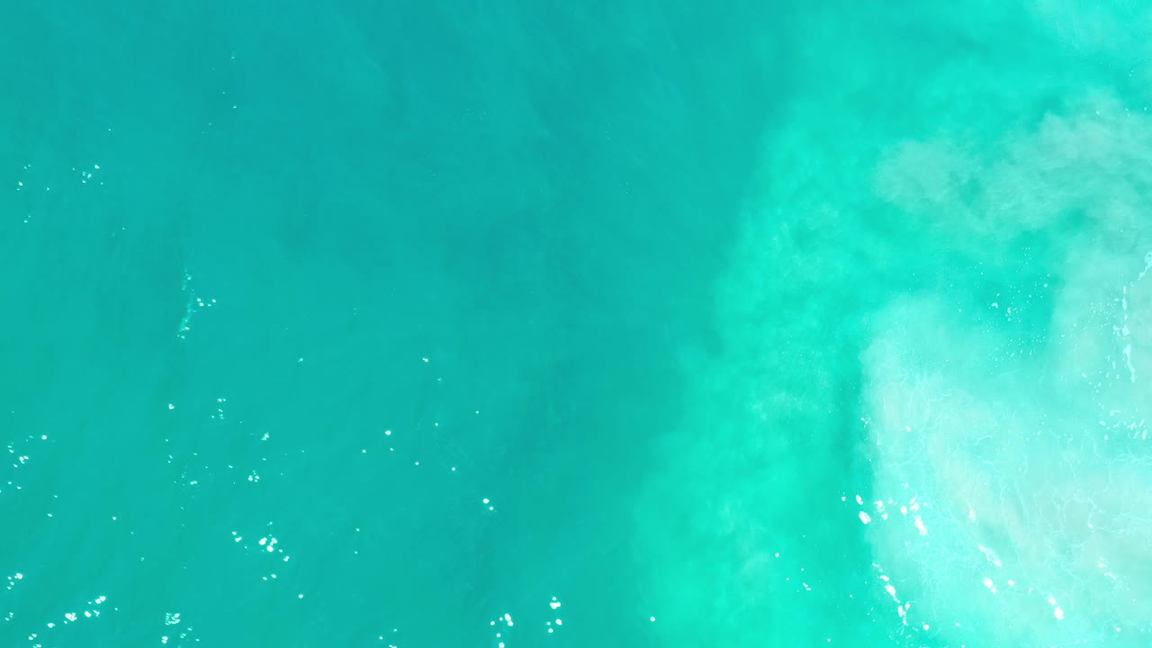 Top-down view of turquoise sea in Los Cabos, Mexico, with a broad pale patch near the center and no visible people.
