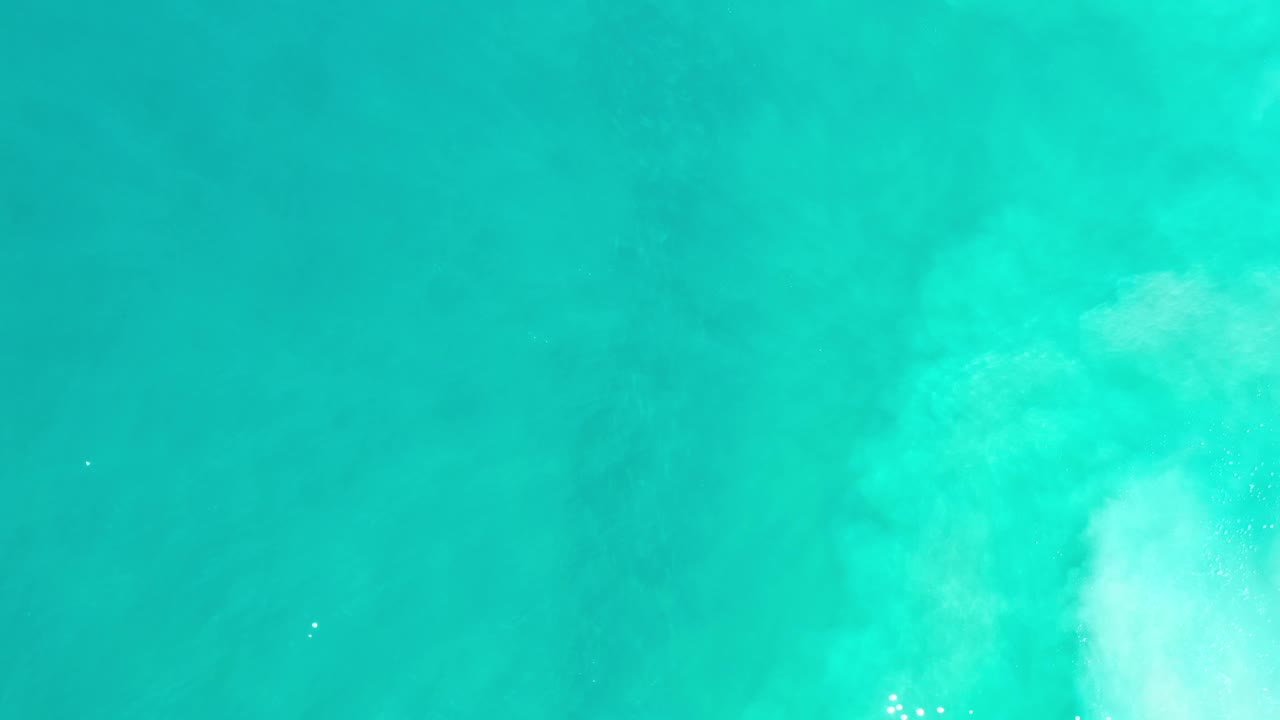 Clear blue-green ocean water in Los Cabos, Mexico with a brighter pale wash rising through the center-right and no visible people.
