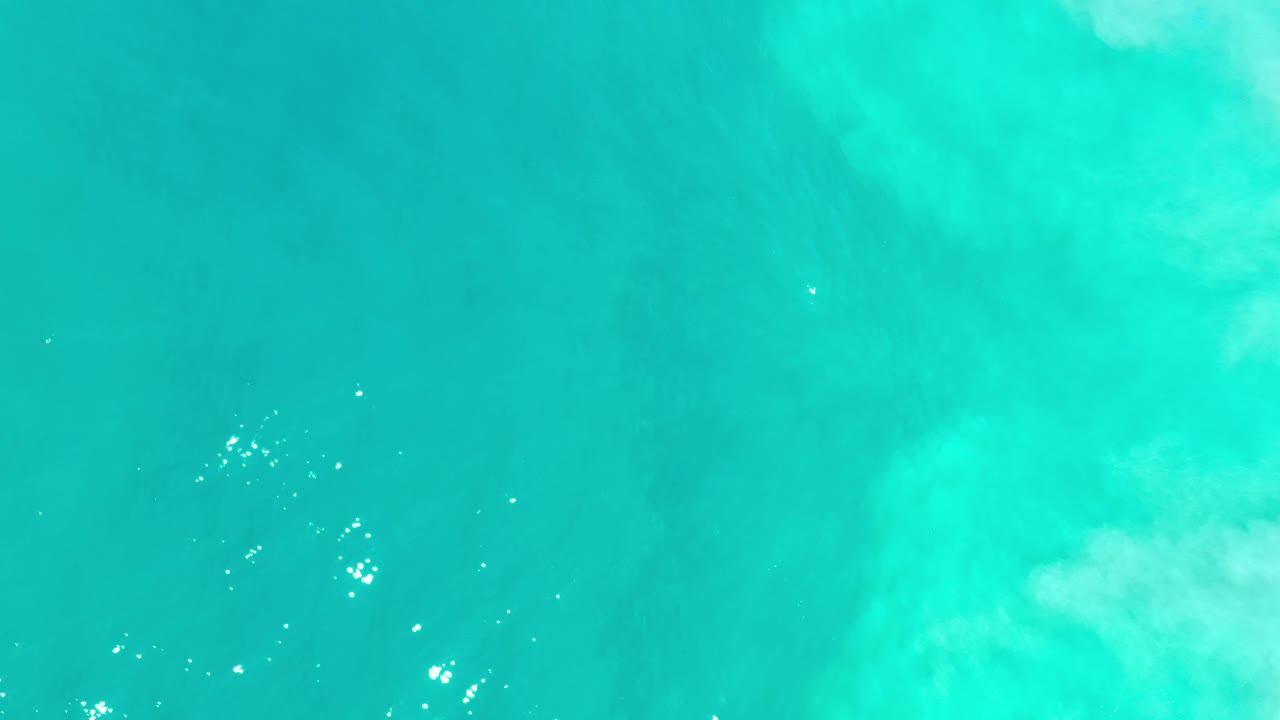 Blue-green ocean surface in Los Cabos, Mexico, with a broad pale cloudlike patch under the water and no visible people.