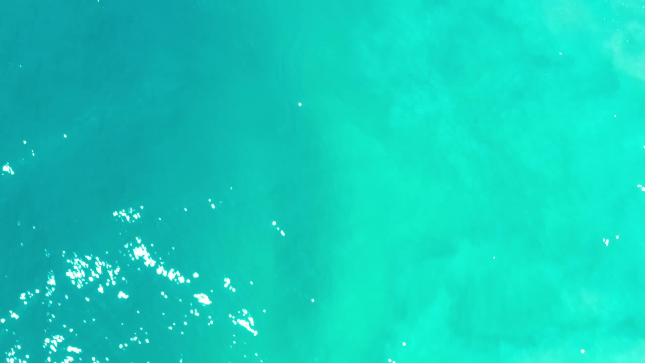 Overhead Los Cabos sea surface with green-blue water, pale submerged patterns, small ripples, and no visible people.