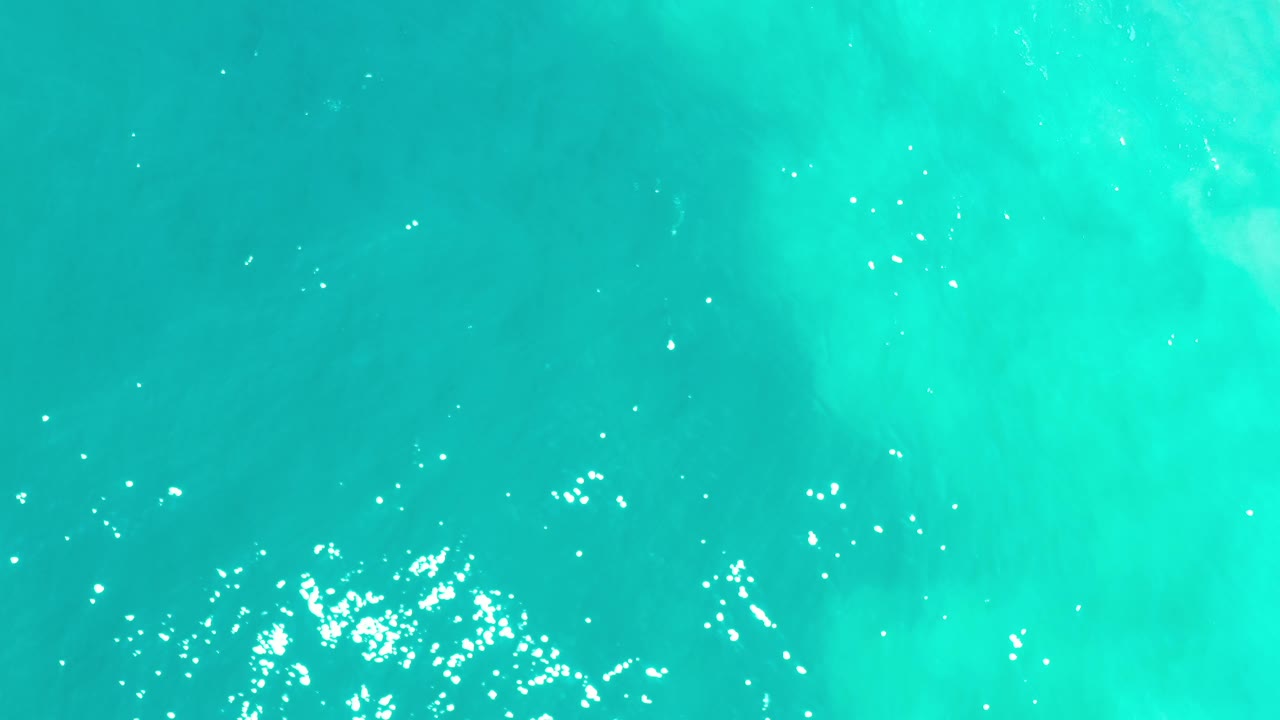 Aerial sea texture with bright glints near the lower edge