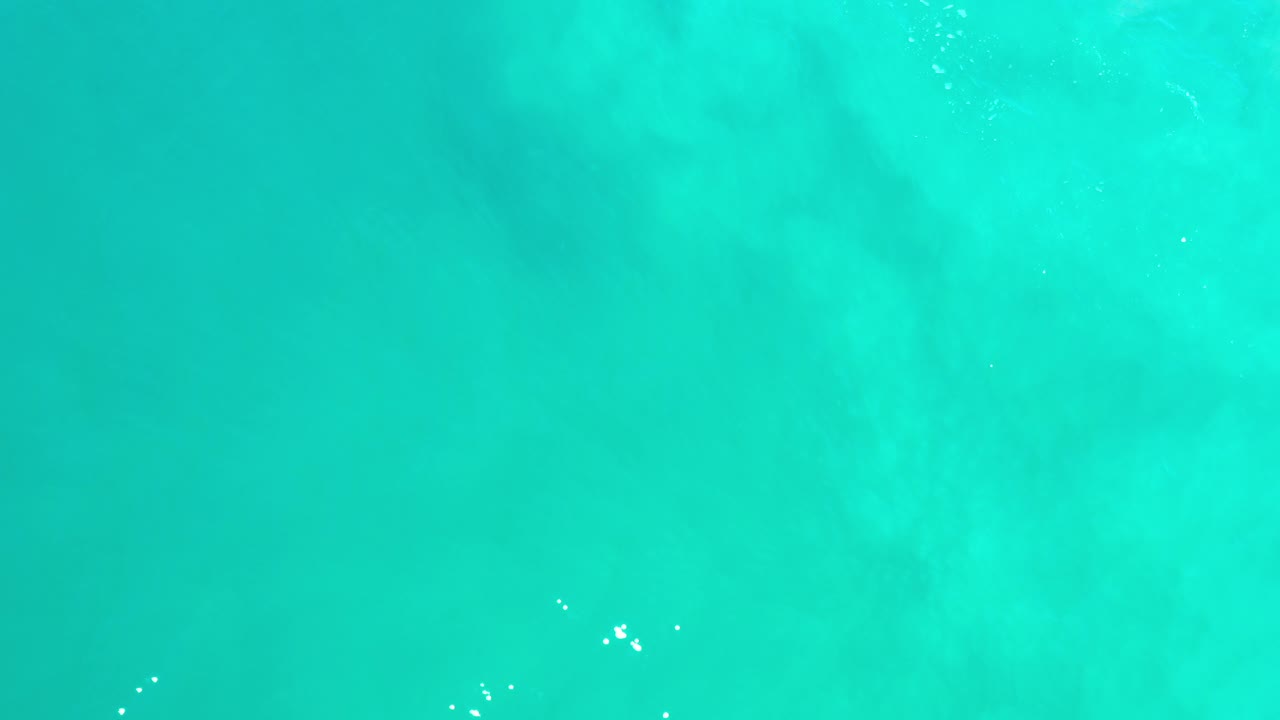 Top-down view of turquoise sea water in Los Cabos, Mexico, with faint underwater texture and no visible people.