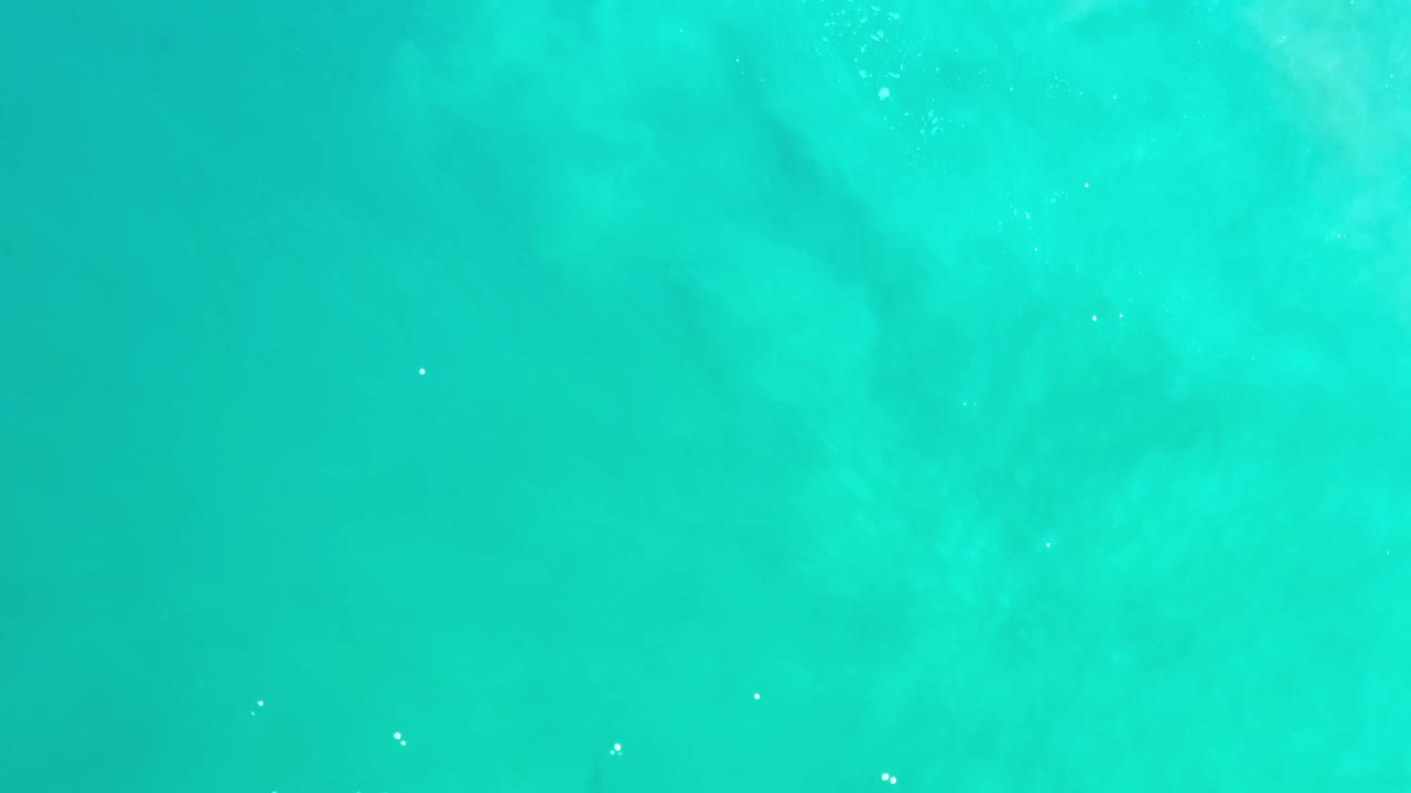 Clear aqua sea in Los Cabos, Mexico, with faint pale underwater patches and no visible people one second into the clip.