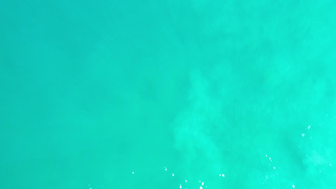 Opening frame of abstract turquoise water texture from Los Cabos, Mexico, with pale cloudlike patches, tiny white highlights, and no visible people.