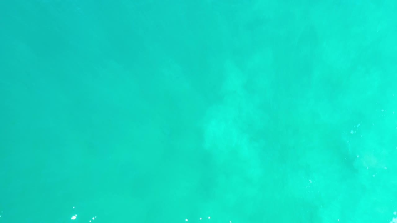 Blue turquoise texture with misty lighter patches and a few reflective specks.