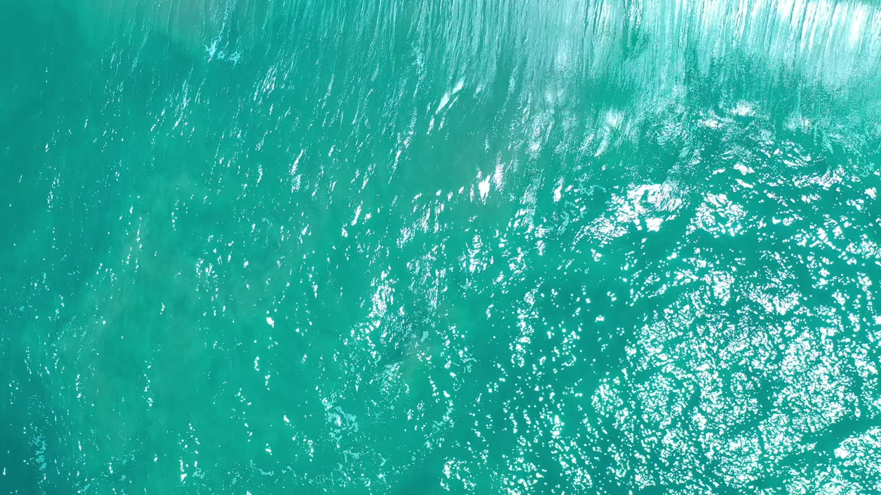 Turquoise sea seen from above with foamy water near the top.