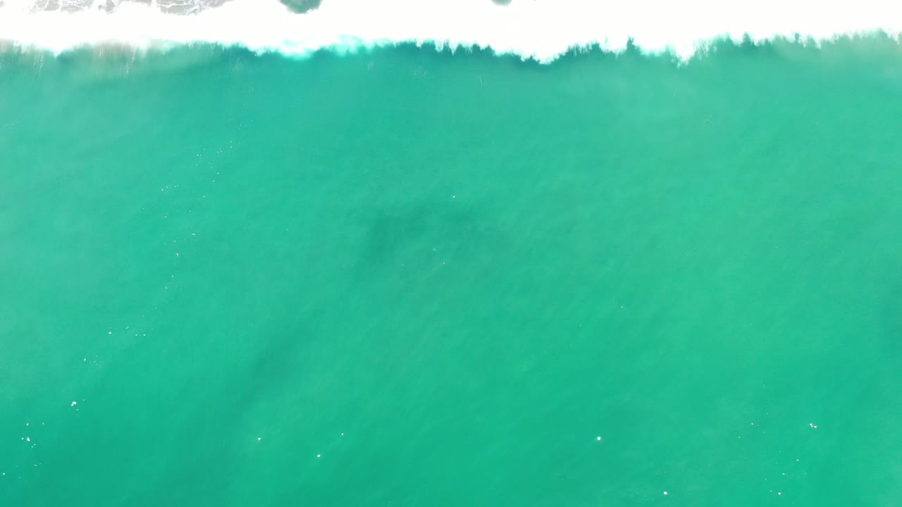 Overhead turquoise ocean with white surf along the top edge.