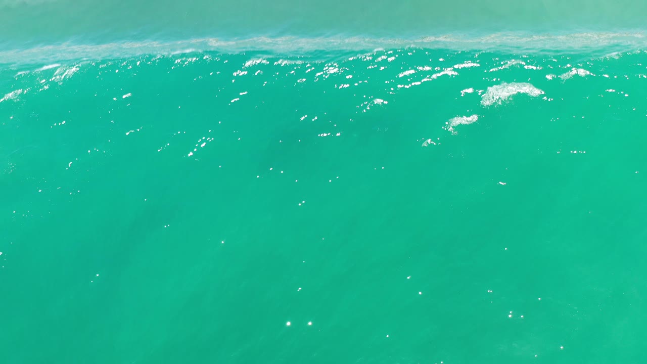 Green-blue ocean surface with stronger ripples and speckled sunlight.