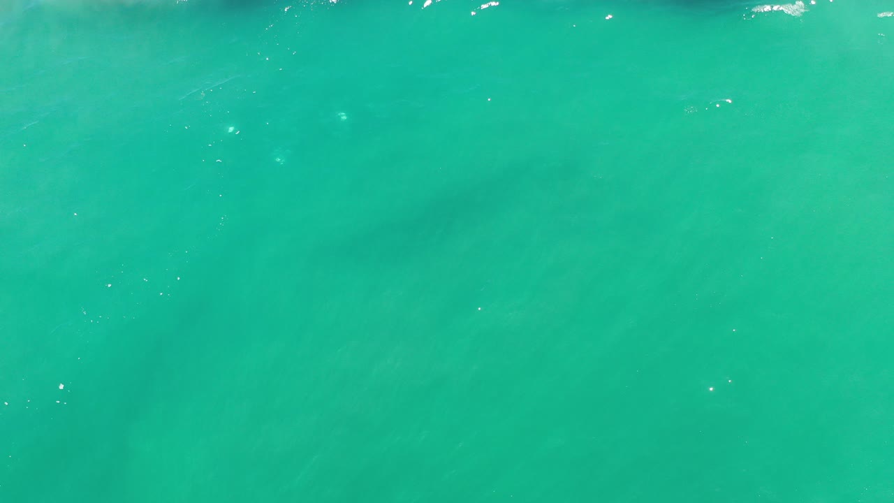 Overhead view of green ocean water in Los Cabos, Mexico, with scattered sunlight flecks and no visible people.