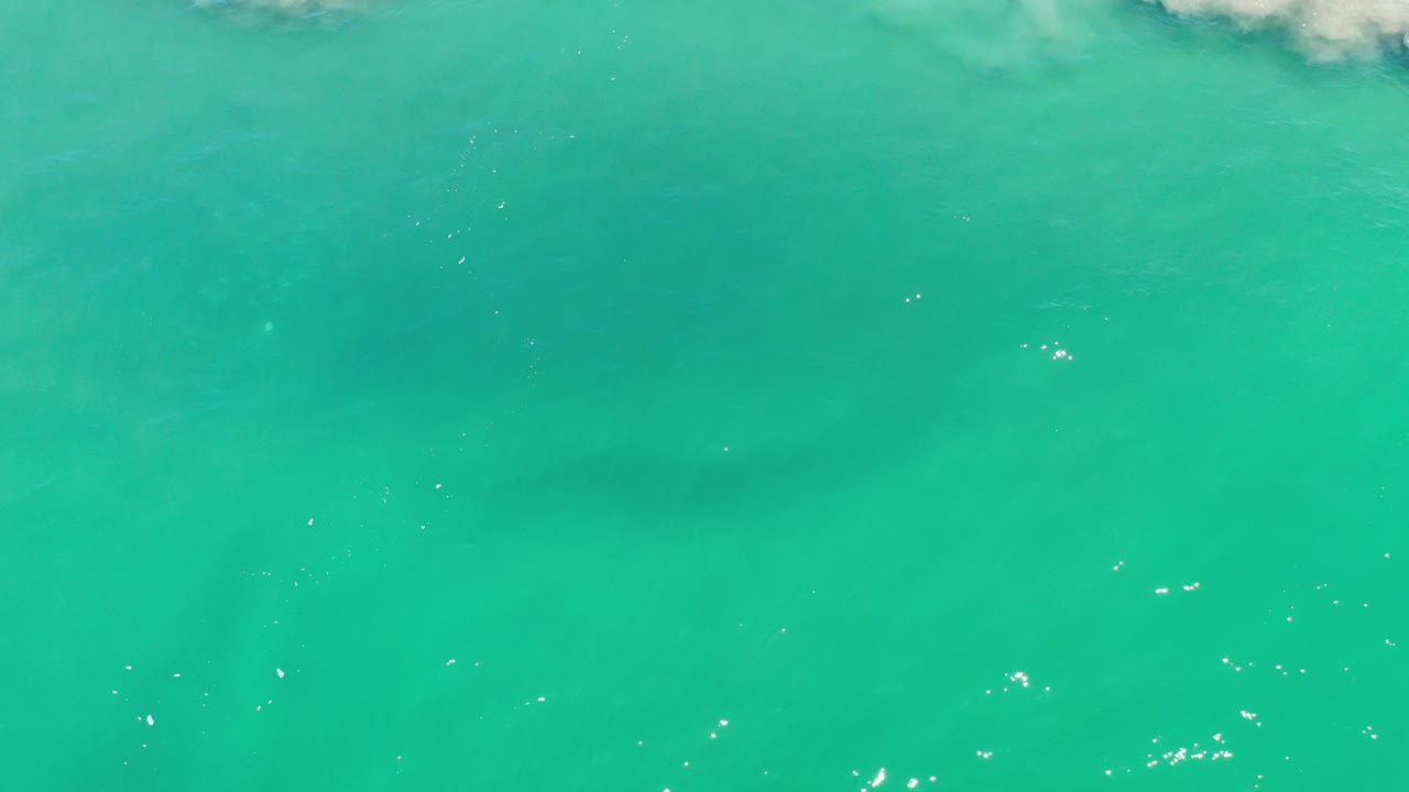 Overhead Los Cabos, Mexico seawater at the opening moment, with white foam near the upper edge, a dark underwater form in the lower half, and no visible people.