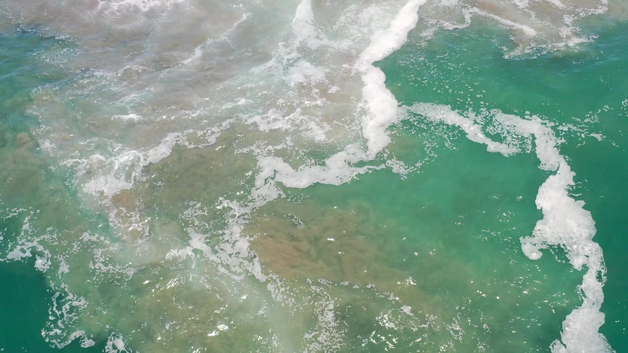Overhead turquoise surf with white foam over sandy shallows