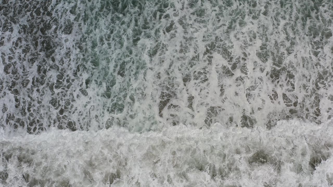 Foamy ocean surface with pale turquoise patches.