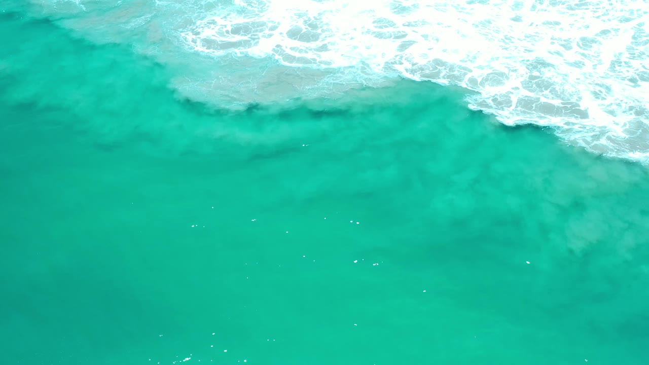 Bright green sea with surf foam crossing the top