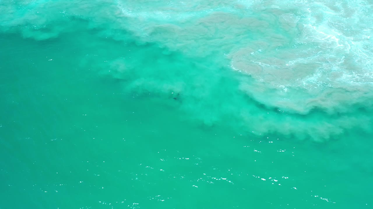 Bright turquoise water with white surf foam across the top.