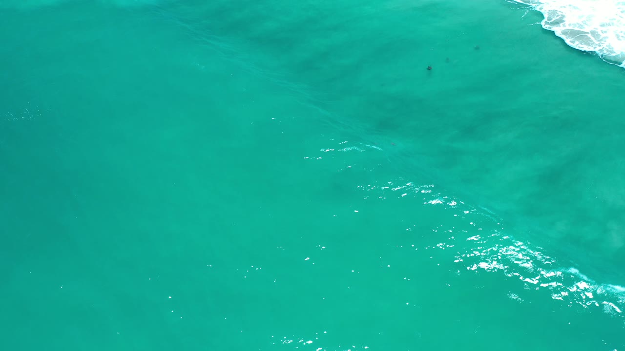 Bright turquoise water with surf foam clipped at the top right corner.