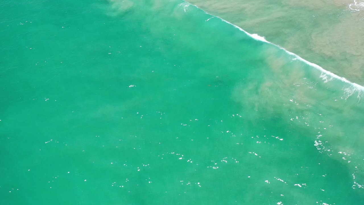 Turquoise shoreline water with a thin white wave near the top right.