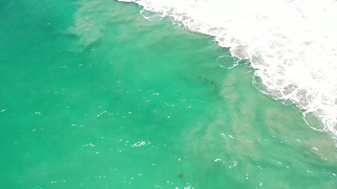 Turquoise water with a diagonal band of white foam along the upper right.